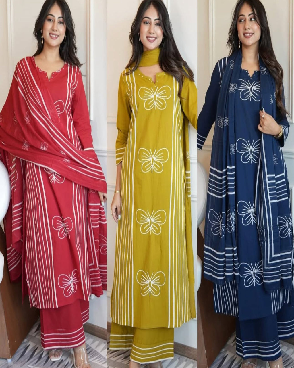 Three women wearing different colored traditional outfits with butterfly patterns.