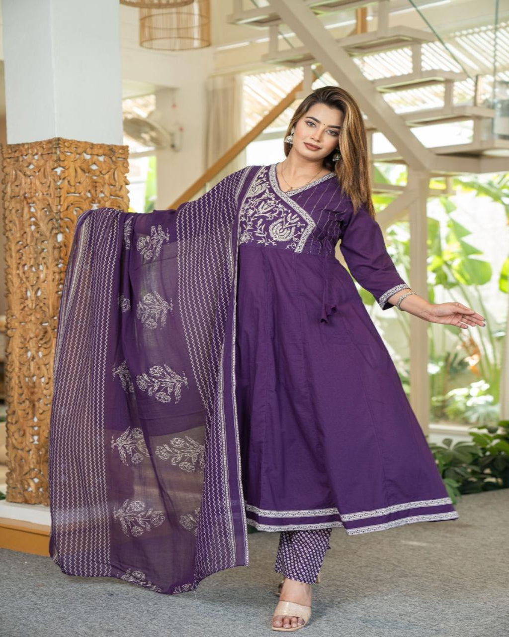 Woman in a purple traditional outfit with a matching dupatta indoors.