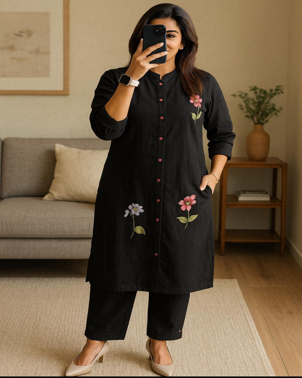 Woman taking a mirror selfie wearing a black embroidered kurta in a living room.