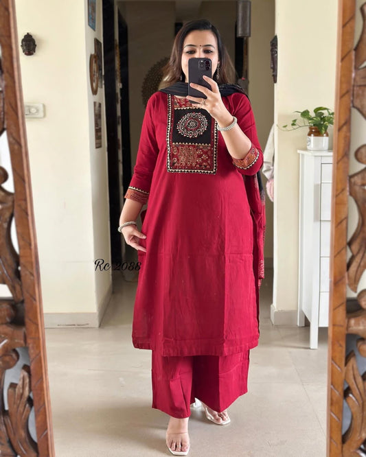 Woman taking a mirror selfie wearing a red traditional outfit with intricate embroidery.