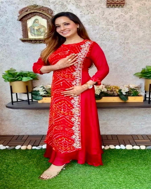 Woman in a red traditional outfit with white patterns standing on grass.