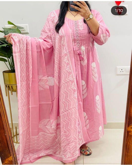 Woman wearing a pink traditional outfit with white patterns in a room.
