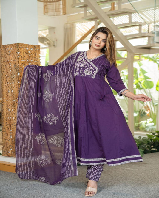 Woman in a purple traditional outfit with a matching dupatta indoors.