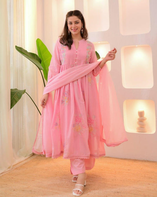Woman in a pink traditional outfit with a matching dupatta in a softly lit room.