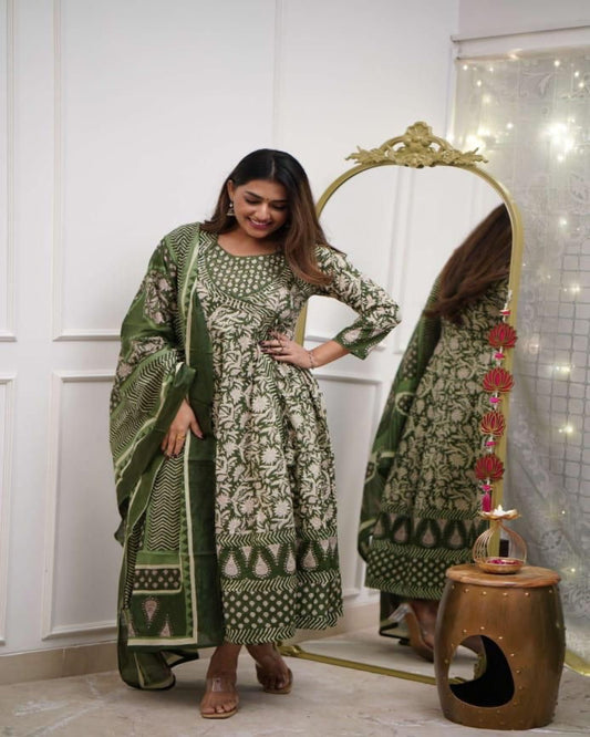 Woman in a green and white patterned dress standing in front of a mirror.