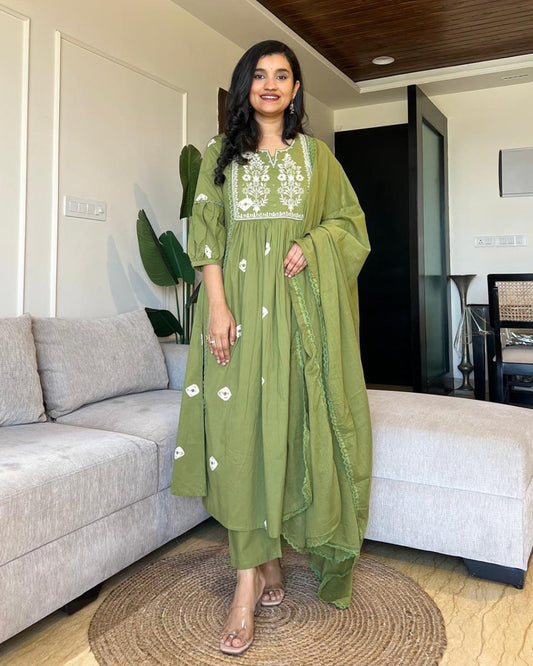 Woman in a green traditional outfit standing in a modern living room.